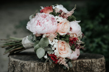 Wedding bouquet of roses with rings on wooden bench