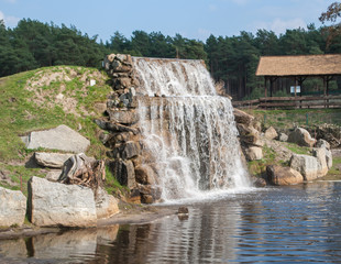 Artificial waterfall in a park surrounded by forest trees