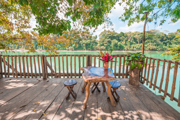 Obraz premium Rustic bench and table aside an emerald river 