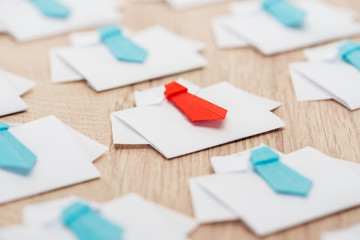 selective focus of origami white shirts with blue ties with one red on wooden table