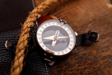 Black leather wallet and old rope with compass on wooden background. Sailor or soldier set concept. 