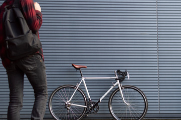 a young guy with a backpack goes to the white bike, the student go to school