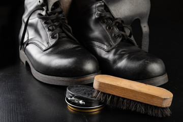 Shoe polish, brush and black military boots. Polishing and cleaning shoes on a black table.