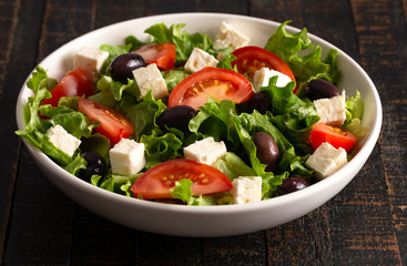 Greek Salad with Olives Tomatos and Feta Cheese on a Rustic Wood Table