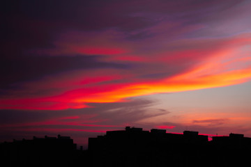 Colorful dark dramatic sky with cloud at sunset and builings in the darkness