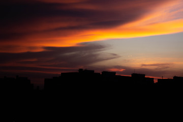 Colorful dark dramatic sky with cloud at sunset and builings in the darkness
