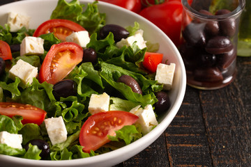 Greek Salad with Olives Tomatos and Feta Cheese on a Rustic Wood Table