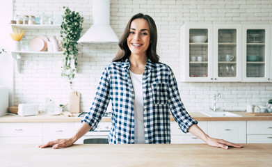 Young beautiful modern woman stands near table on kitchen at home.
