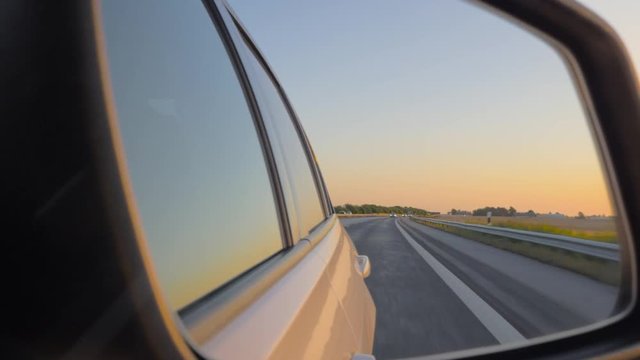 Close-up of the side view car mirror at sunset