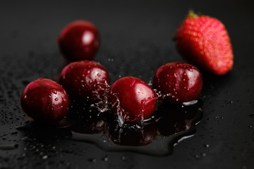 Sweet cherries with strawberries in drops of water