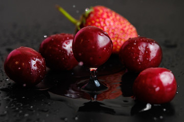 Sweet cherries with strawberries in drops of water