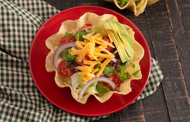 Taco Salad in a Crunch Corn Tortilla Bowl Isolated on Wooden Table