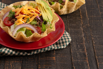 Taco Salad in a Crunch Corn Tortilla Bowl Isolated on Wooden Table
