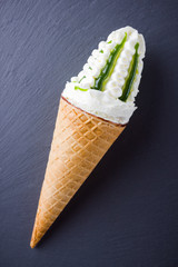 Ice cream cone on a slate board. Waffle cone with ice cream on slate board. Dessert with jam on black background. Flat lay