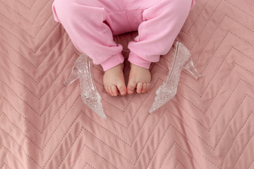Cinderella story. Baby girl's feet and crystal shoes on the pink blanket