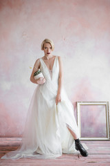 Fototapeta na wymiar Fashionable brave bride of this year. Short haircut, long wedding dress. Bouquet in hand.