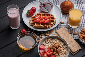 Oatmeal. Breakfast. Food. Muesli. Snack. Morning meal. Fresh waffles. Strawberry, honey, jam, almond and muffin on black table background