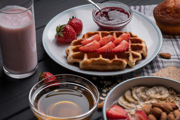 Oatmeal. Breakfast. Food. Muesli. Snack. Morning meal. Fresh waffles. Strawberry, honey, jam, almond and muffin on black table background