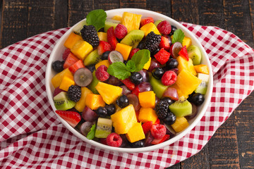 A Bowl of Fresh Rainbow Fruit Salad on a Wooden Table