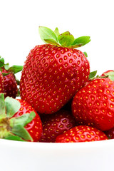 RED STRAWBERRIES WITH GREEN LEAVES IN BOWL ON WHITE BACKGROUND
