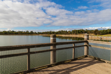 Obraz premium A walk bridge on a large fresh water lake in a community park.