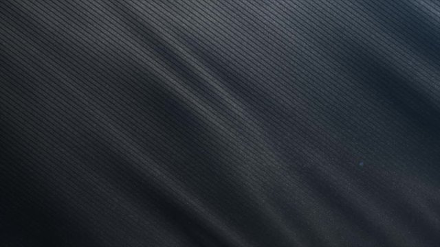 Black lined fabric cloth is waving close up shot. 