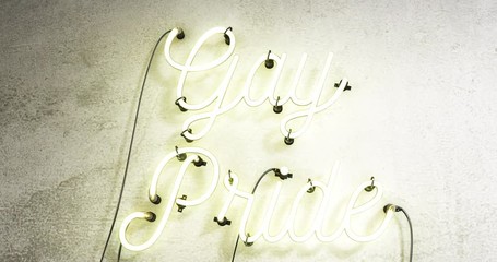White bright neon sign that says Gay Pride on a grey concrete wall background, the footage starts with the sign off, then it stays on for 30 seconds them flashes on and off for another 30 seconds. - Powered by Adobe