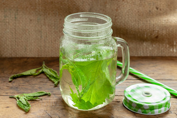 nettle herbal tea at jar on a wooden background. fresh medicine nettle. background decorating with nettle leafs. traditional herbal medicine concept.