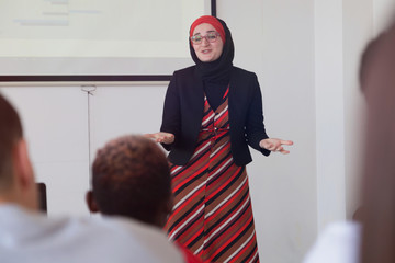 Female muslim professor explain lesson to students and interact with them in the classroom.Helping...