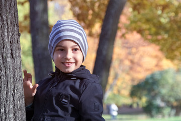 portrait of a young boy with a smile on his face near a tree in the Park in autumn