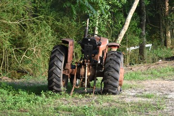 An old Massey Ferguson tractor sits abandoned with a flat tire at the edge of a field on a southern farm.