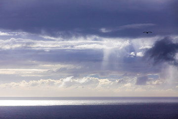 Fototapeta na wymiar Dramatic sky over Atlantic Ocean coast near Sao Miguel Island, the largest island in the archipelago of the Azores, Portugal. Dark stormy clouds in the sky and strip of sunlight over the ocean surface