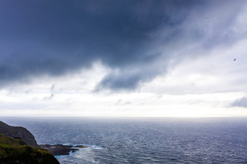 Dramatic sky over Atlantic Ocean coast near Sao Miguel Island, the largest island in the archipelago of the Azores, Portugal. Dark stormy clouds in the sky over the ocean