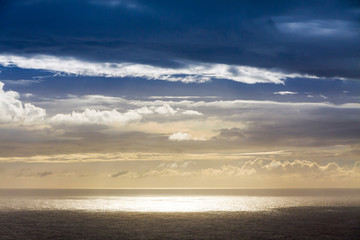 Fototapeta na wymiar Dramatic sky over Atlantic Ocean coast near Sao Miguel Island, the largest island in the archipelago of the Azores, Portugal. Dark stormy clouds in the sky and strip of sunlight over the ocean surface