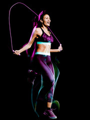 one beautiful caucasian mixed race woman exercising  jumping rope fitness exercises in studio isolated on black background