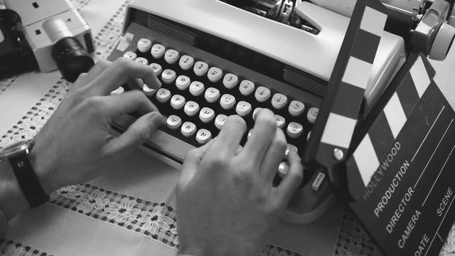 Filmmaker typing a letter on a typewriter. 50's 60's 70's vintage scene. Historical reenactment concept.