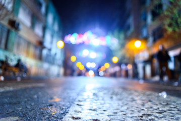 Urban night scene with people walking out of focus with colored background.