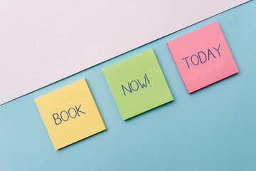 Text sign showing Book Now. Business photo showcasing guaranteed to have place because you have already purchased it Pastel colour note papers placed sideways on the of softhued backdrop