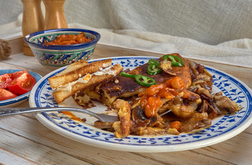Omelet with fried onions and mushrooms.Baked beans and fresh tomatoes.On a wooden tray.