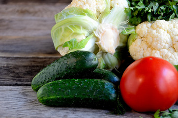 Cauliflower, tomato, cucumbers on a wooden table.