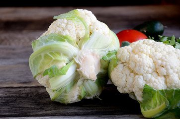 Cauliflower, tomato, cucumbers on a wooden table.