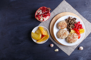 meatballs with rice mushrooms, sweet peppers and pomegranate seeds on black wooden background.