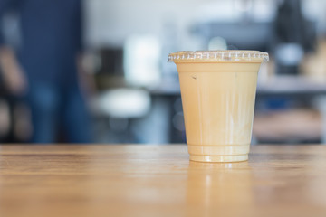 Iced milk coffee in plastic cup with cover.no straw.Indoor cafe