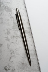 Notepad with metal gray pen on a stone background. Concept elegant business style. Top view, flat lay.