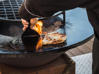 Cook prepares ribs on a circular grill