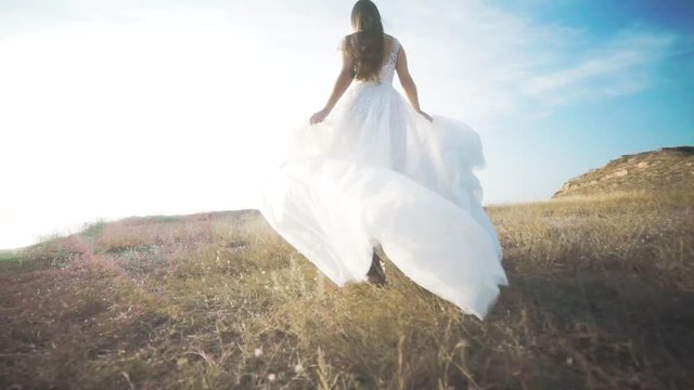 Running bride in amazing long dress through the landscape. Happy moments
