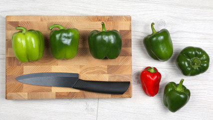 sweet peppers with a ceramic knife on a wooden board
