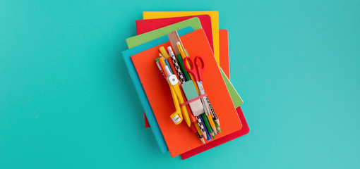 Stack of notebooks and supplies on blue background.