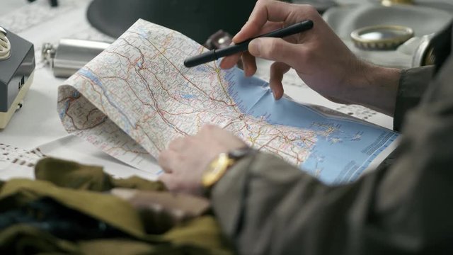 A soldier using a map to build a strategy. 50's 60's 70's vintage scene. Historical reenactment concept.