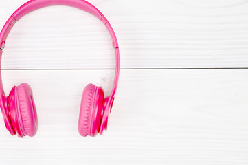 Pink headphones for listening to sound and music on a wooden background